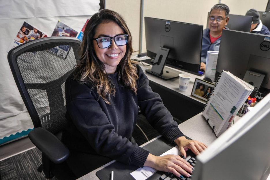 a student sitting behind a computer smiling