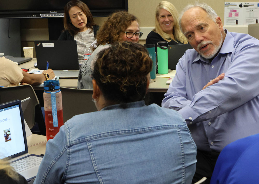 Dr. Paul Porter speaking with one of the DLAC team members in the classroom.