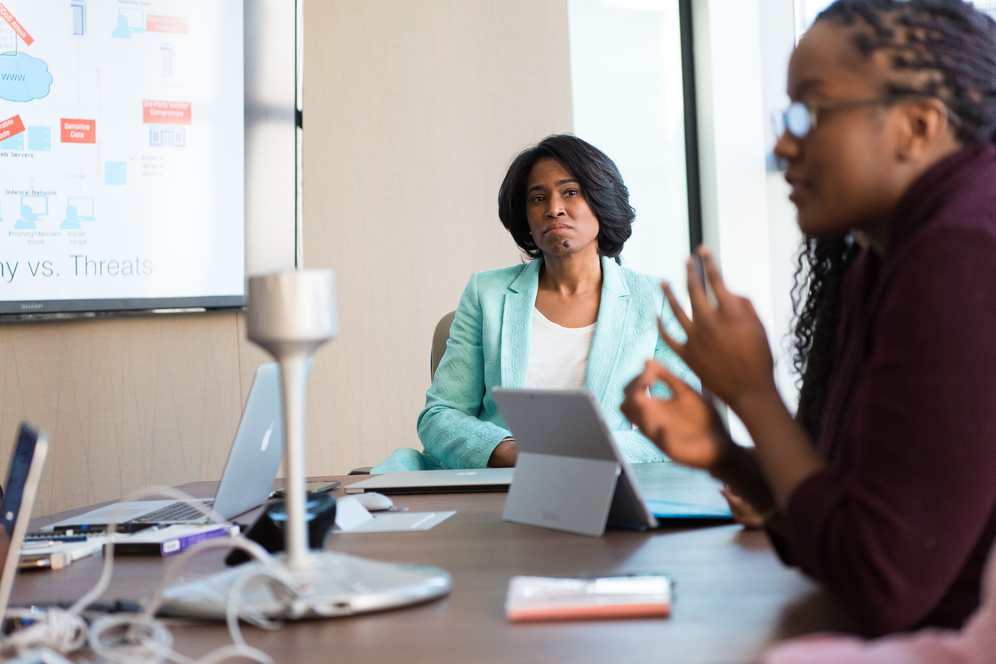 Two women sitting at a table in a work meeting room.